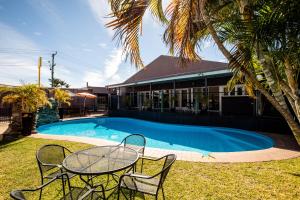 Biloela定居者酒店的游泳池旁边的一张桌子和几把椅子