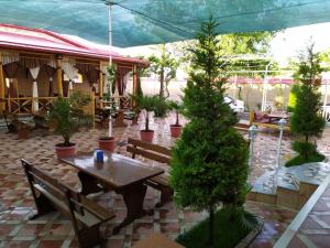 a patio with a table and benches and potted trees at Xum Don in Samarkand