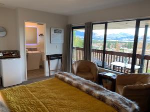 een slaapkamer met een bed en een balkon met uitzicht op de bergen bij 8 on Oregon Boutique Lodge in Hanmer Springs