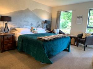 a bedroom with a bed, chair, table and window at 8 on Oregon Boutique Lodge in Hanmer Springs