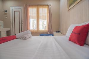 a bedroom with a large white bed with red pillows at RedDoorz at Amellia Pasteur Bandung in Bandung +37 photos