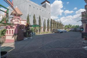 eine Straße mit einem rosa Gebäude und einem Parkplatz in der Unterkunft RedDoorz near Setrasari Mall 2 in Bandung