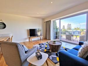 a living room with a blue couch and a large window at Phoenix Apartments in Lorne