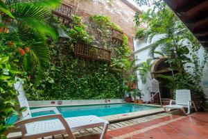 a swimming pool with two chairs next to a building at Hotel Don Pedro De Heredia in Cartagena de Indias