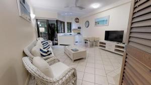 
a living room filled with furniture and a tv at The Pavilions in Port Douglas
