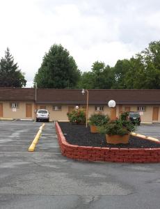 a parking lot in front of a building with plants at Hallmark Motel in Cinnaminson