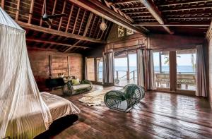 a bedroom with a bed and chairs and the ocean at Villa Tao in Tabanan +96 photos