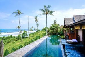 a swimming pool in front of a house with a view of the ocean at Villa Tao in Tabanan