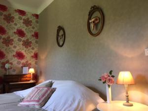 - une chambre avec un lit, une lampe et des fleurs sur le mur dans l'établissement Le Plein Air, à Saint-Étienne-au-Mont