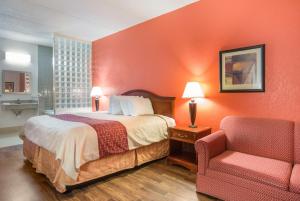 a bedroom with a bed, chair, lamp and a desk at Budgetel Inns & Suites - Atlanta Galleria Stadium in Atlanta
