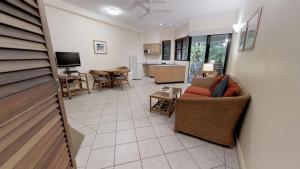 
a living room filled with furniture and a tv at The Pavilions in Port Douglas
