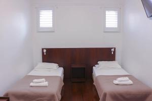 two beds in a room with a white wall at Glasgow Arms Hotel Ultimo in Sydney