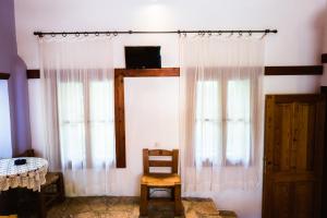 Cette chambre dispose de deux fenêtres, d'une chaise et d'une table. dans l'établissement Karnayo, à Megísti