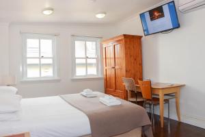 a bedroom with a bed and a desk and a tv at Glasgow Arms Hotel Ultimo in Sydney