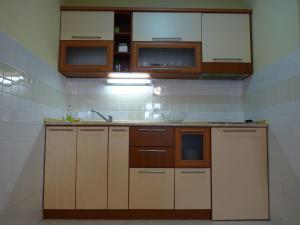 La cuisine est équipée de placards marron et blancs et d'un évier. dans l'établissement Adeona Apartments, à Ohrid