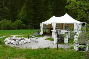 a white tent with a table and chairs in a yard at Waldcamp Frank in Wildalpen