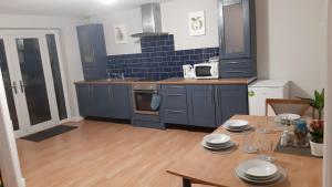 a kitchen with blue cabinets and a table with plates on it at Sunny Lynn in Oldham