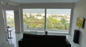 a living room with a couch and a large window at AllSeasonsApartment in Kalamata