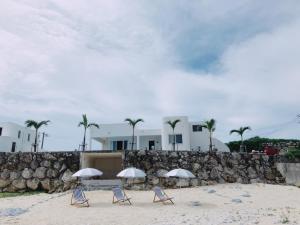 eine Gruppe von Stühlen und Sonnenschirmen am Strand in der Unterkunft Thalassa Beach and Pool Villa in Yoron