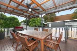 Beautiful Queenslander في تاونزفيل: طاولة وكراسي خشبية على سطح مع مروحة سقف