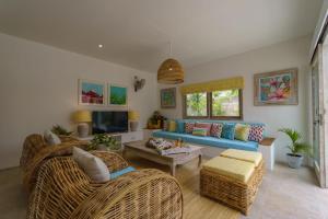 - un salon avec un canapé bleu et des fauteuils en osier dans l'établissement Sunyi Villas, à Kuta Lombok
