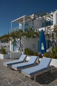 a row of blue lounge chairs and a surfboard at Paroscarmel studio-apartment in Logaras