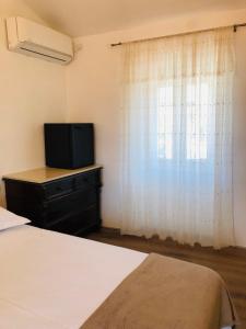 1 dormitorio con 1 cama, TV y ventana en Nona Beta, en Mali Lošinj