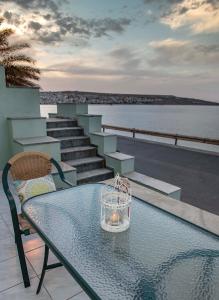 een glazen tafel met een kaars op het balkon bij Sunrise Beachfront Apartment in Sitia
