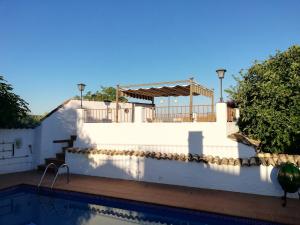 a white wall and a swimming pool with a house at Cortijo Los Abedules in Cazorla