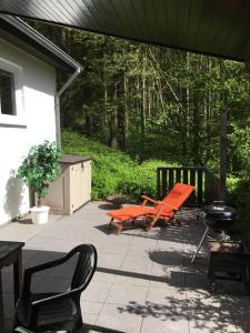 a patio with two orange chairs and a grill at Ferienhaus 956 in Biersdorf am See