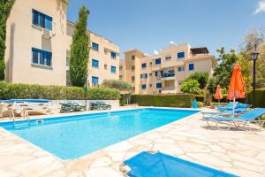 uma piscina com cadeiras e um edifício em Kings Apartment with private Garden em Pafos