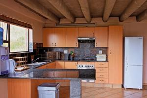 a kitchen with wooden cabinets and a white refrigerator at Mahikeng Lodge in Magaliesburg