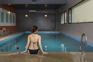a woman sitting in a swimming pool with a glass of wine at Terracotta Hotel & Resort Dalat in Da Lat
