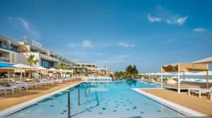 a swimming pool with chairs and umbrellas at a resort at Marea Suites, Valamar Collection in Poreč