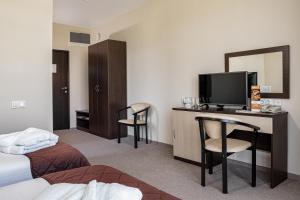 ein Hotelzimmer mit einem Bett und einem Schreibtisch mit einem TV in der Unterkunft Barkhatnye Sezony Yekaterininsky Kvartal Resort in Adler