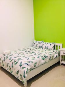a bed in a room with a green wall at Homestay BONO Mũi Né in Phan Thiet