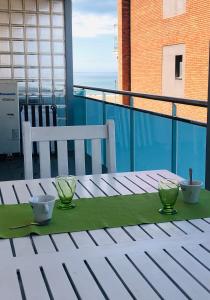 una mesa con 2 tazones y 2 tazas en un balcón en Lets Holidays New Flat Beachfront In Castelldefels, en Castelldefels