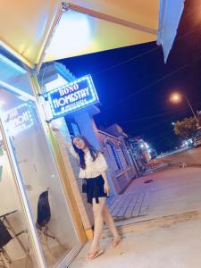 a woman is standing in front of a sign at Homestay BONO Mũi Né in Phan Thiet