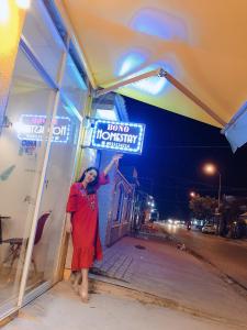 a woman standing in front of a building with a sign at Homestay BONO Mũi Né in Phan Thiet