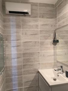 a bathroom with a sink and a wall with tiles at Studio cabine au Grau du roi à 3min à pied de la plage in Le Grau-du-Roi