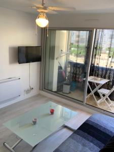 a glass table in a living room with a tv at Studio cabine au Grau du roi à 3min à pied de la plage in Le Grau-du-Roi