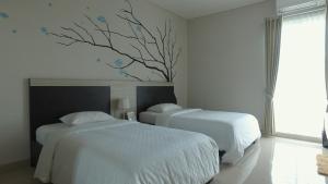 a bedroom with two beds and a tree mural on the wall at Dipan Guest House Yogyakarta in Yogyakarta