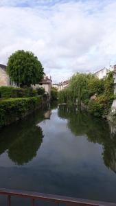 uma vista para um rio com árvores e edifícios em la maison rose: lieu atypique em Nemours