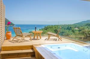 a hot tub on a deck with chairs and a table at Agorastos Hotel in Koinyra