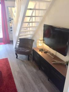 sala de estar con TV, silla y escaleras en Maison à l'Amélie Plage, 300 mètres de la plage/mer, en Soulac-sur-Mer