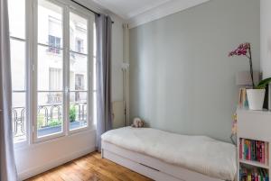 a bedroom with a bed and a large window at Veeve - Eiffel Elegance in Paris