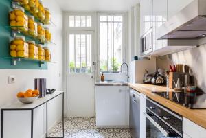 a kitchen with white cabinets and oranges on the counter at Veeve - Eiffel Elegance in Paris