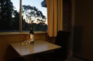 una botella de vino en una mesa frente a una ventana en Panorama Motor Inn, en Newcastle