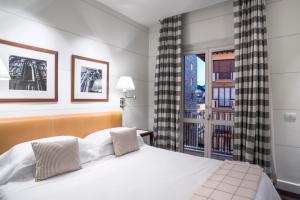 a bedroom with a large white bed and a window at Gallery Hotel Art - Lungarno Collection in Florence