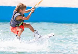 Un jeune garçon sur une planche de surf dans l'eau dans l'établissement Les Chalets de Condrieu, à Condrieu